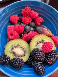 A bowl of berries, kiwi, and figs,